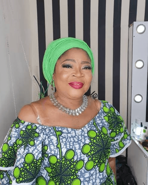 In a dressing room before a show, green gele
